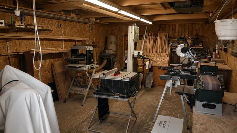 Blick in die helle Werkstatt in Tribsees mit Hobelbänken, Regalen voller Holzobjekte und warmem Tageslicht