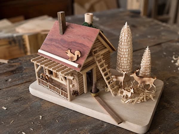 Winterhaus aus Holz mit Leiter, Spanbäumen, Rehen und Eichhörnchen auf dem Dach